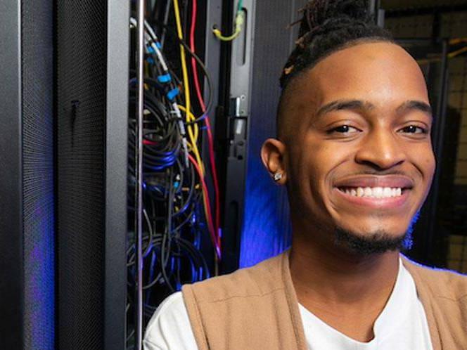 Man smiling for picture with eletrical panel wires coming out of it behind him